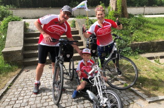 Image is of Leanne, her husband and son, all with their bikes and wearing cycling kit