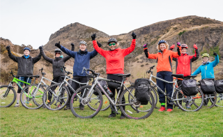 Leanne and a group of cyclists with their bikes, standing in Holyrood Park, Leanne is at front and centre of the group 