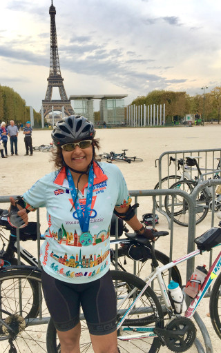 Image of Kris standing with her bike, wearing a medal. In the background is the Eiffel Tower