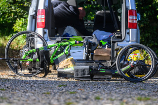 A racing recumbent bicycle on the floor behind a van